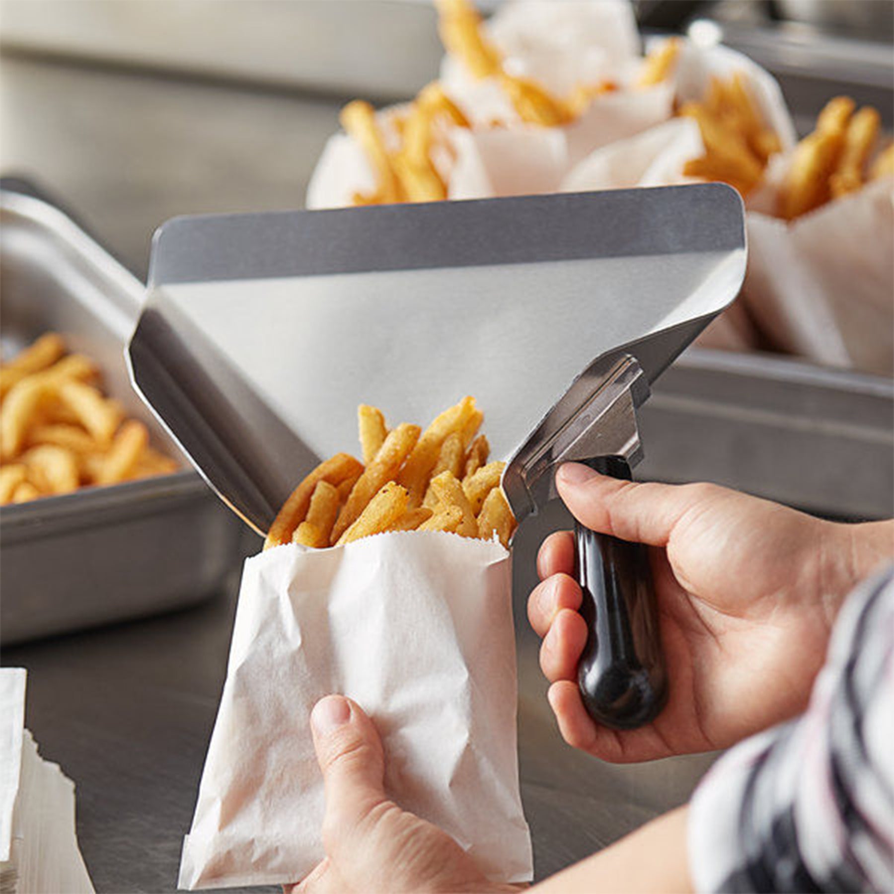 Professional French fry bag filler scoop in use for fast food serving
